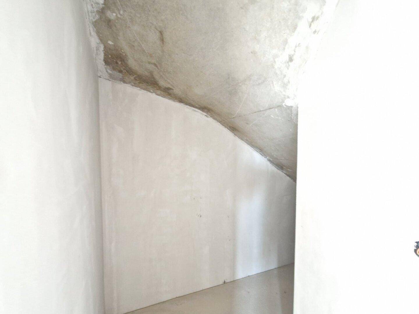 Unfertiger Bereich mit schräger Decke, möglicherweise unter einer Treppe gelegen im Rohbau.