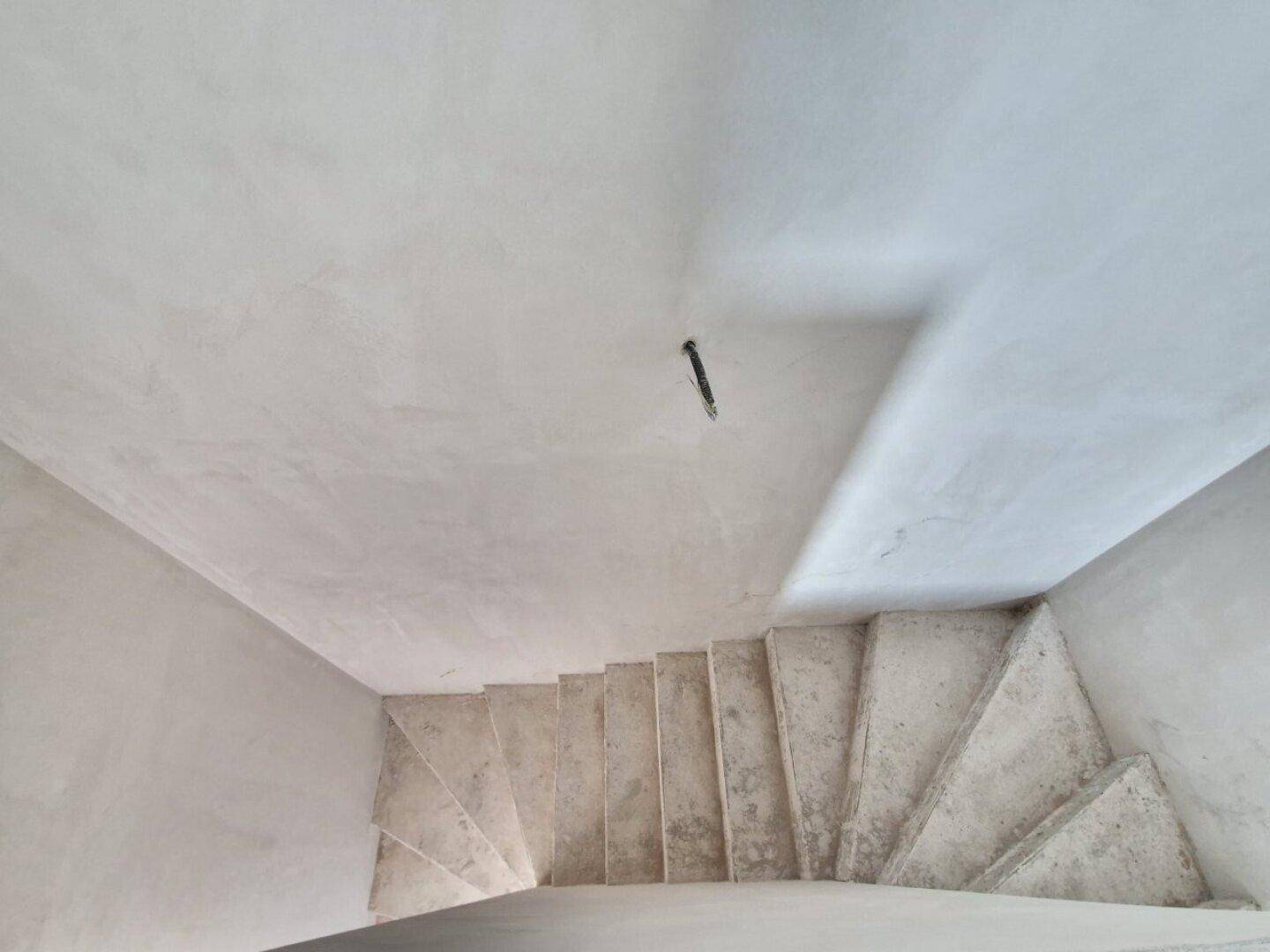 Unfertige Betontreppe führt in das obere Stockwerk des Neubaus im Rohbauzustand.
