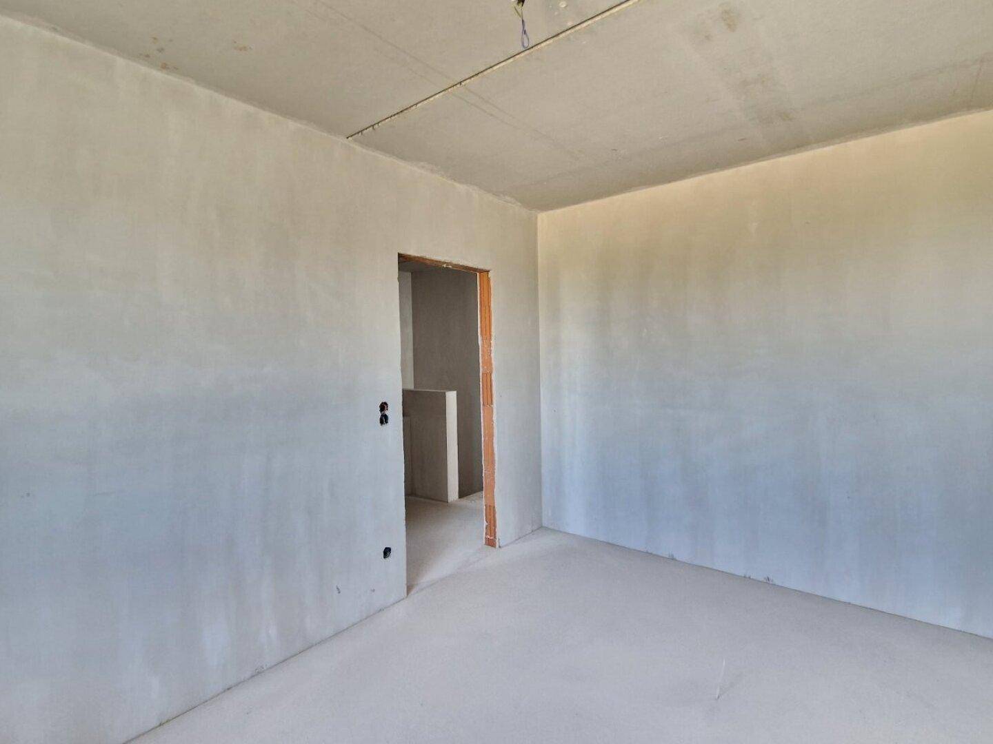 Unfertiger Innenraum mit rohen Wänden und Betonboden, bereit für den Ausbau des neuen Zuhauses.