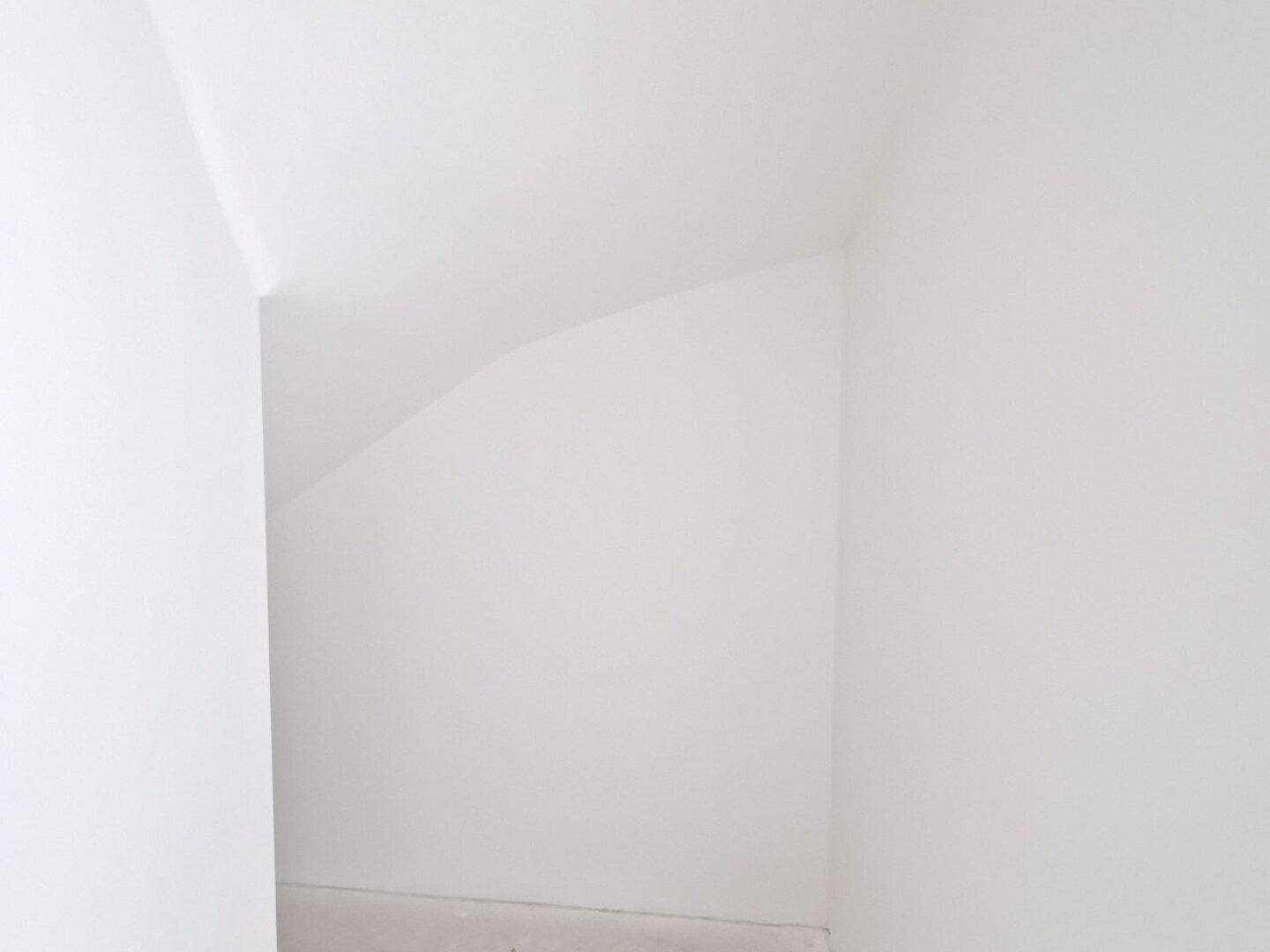 Kleiner Abstellraum im Rohbau mit schräger Decke, ideal für zusätzlichen Stauraum.