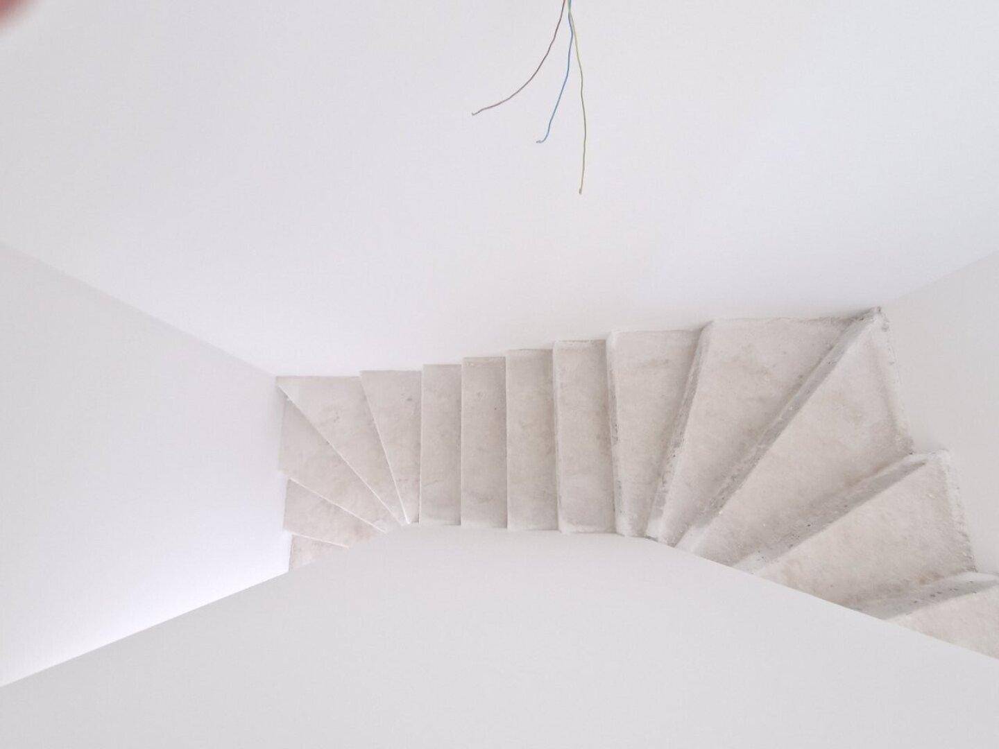 Blick von oben auf die im Rohbau befindliche Treppe, die die Stockwerke verbindet.