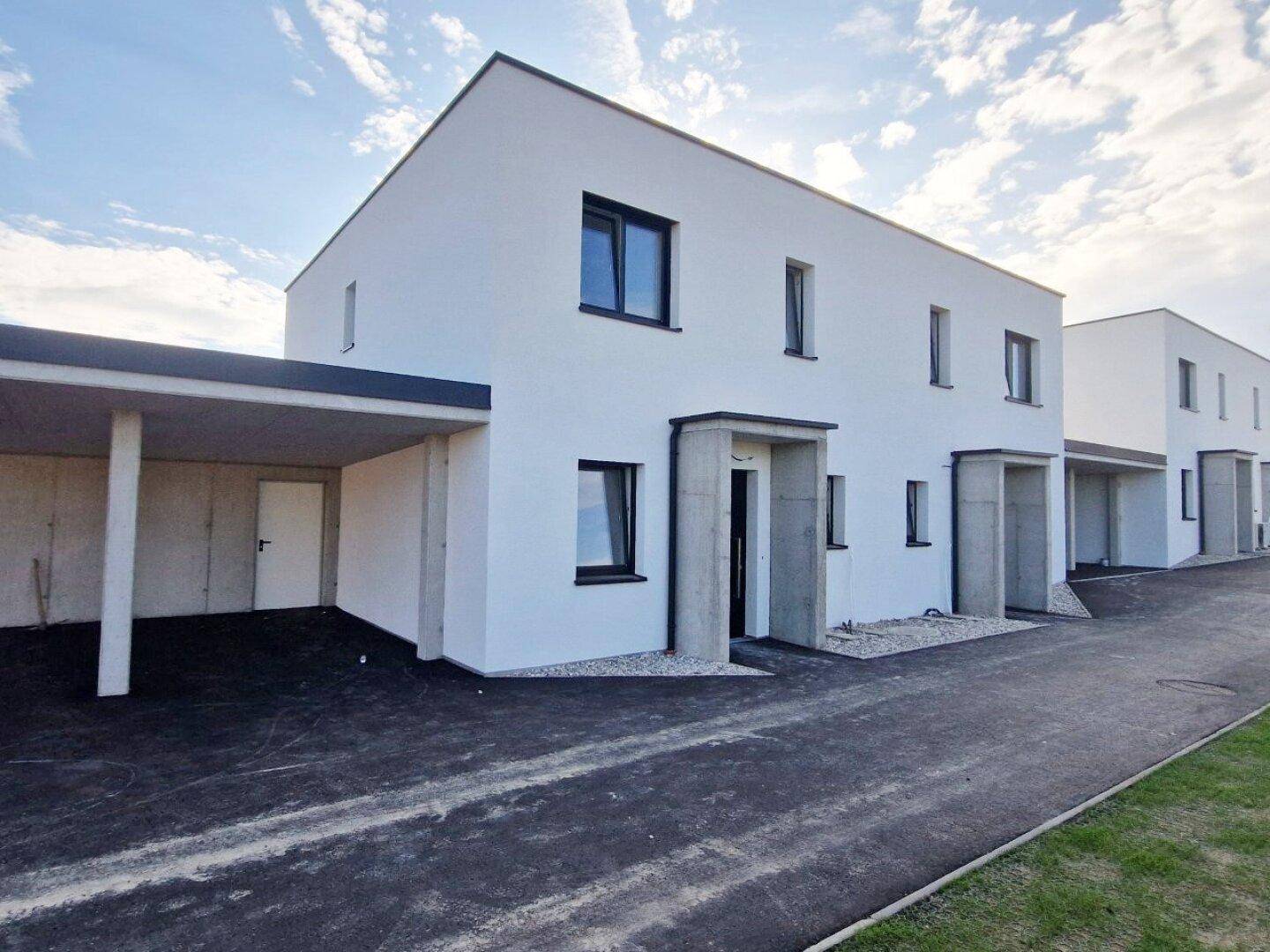 Reihenhäuser in moderner Architektur mit weißer Fassade und integriertem Carport.