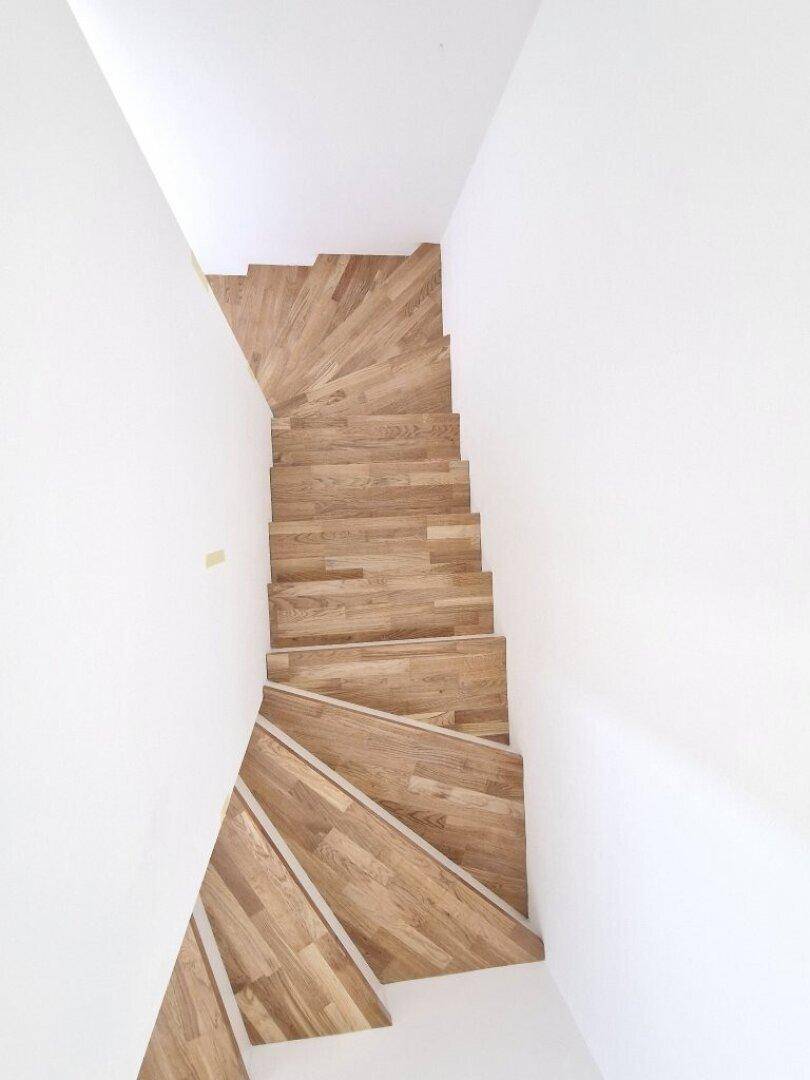 Moderne Holztreppe mit elegantem Design, die verschiedene Etagen miteinander verbindet.