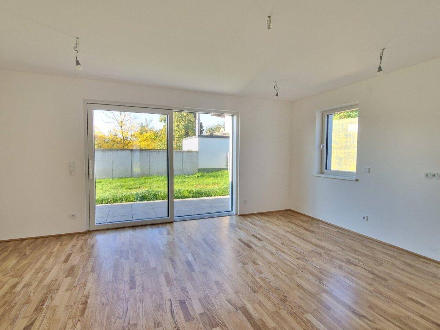 Helles Wohnzimmer mit Holzboden und großer Schiebetür zum Garten.