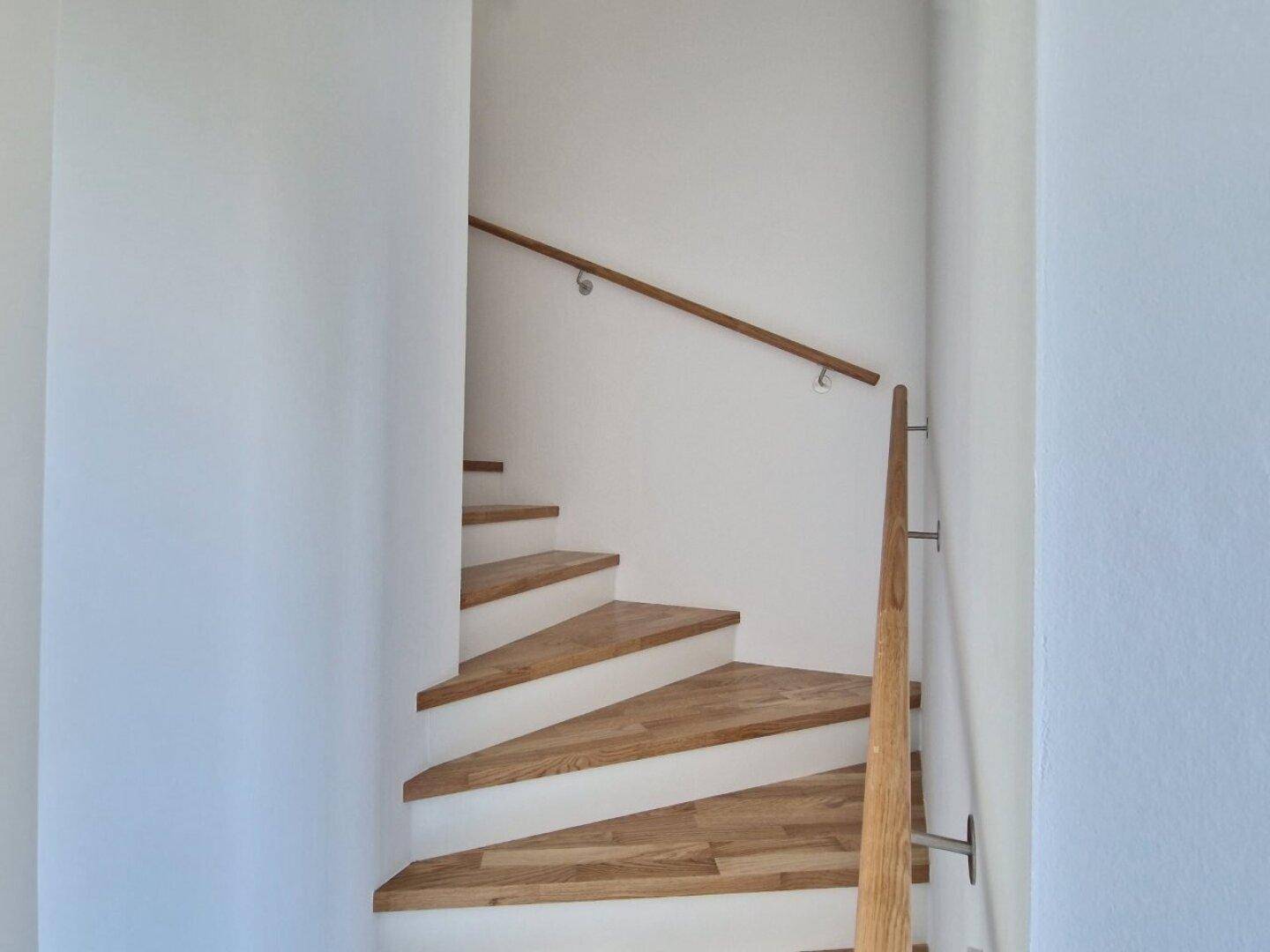 Treppenhaus mit Holzstufen und schlichtem Holzgeländer, führt in die oberen Etagen.