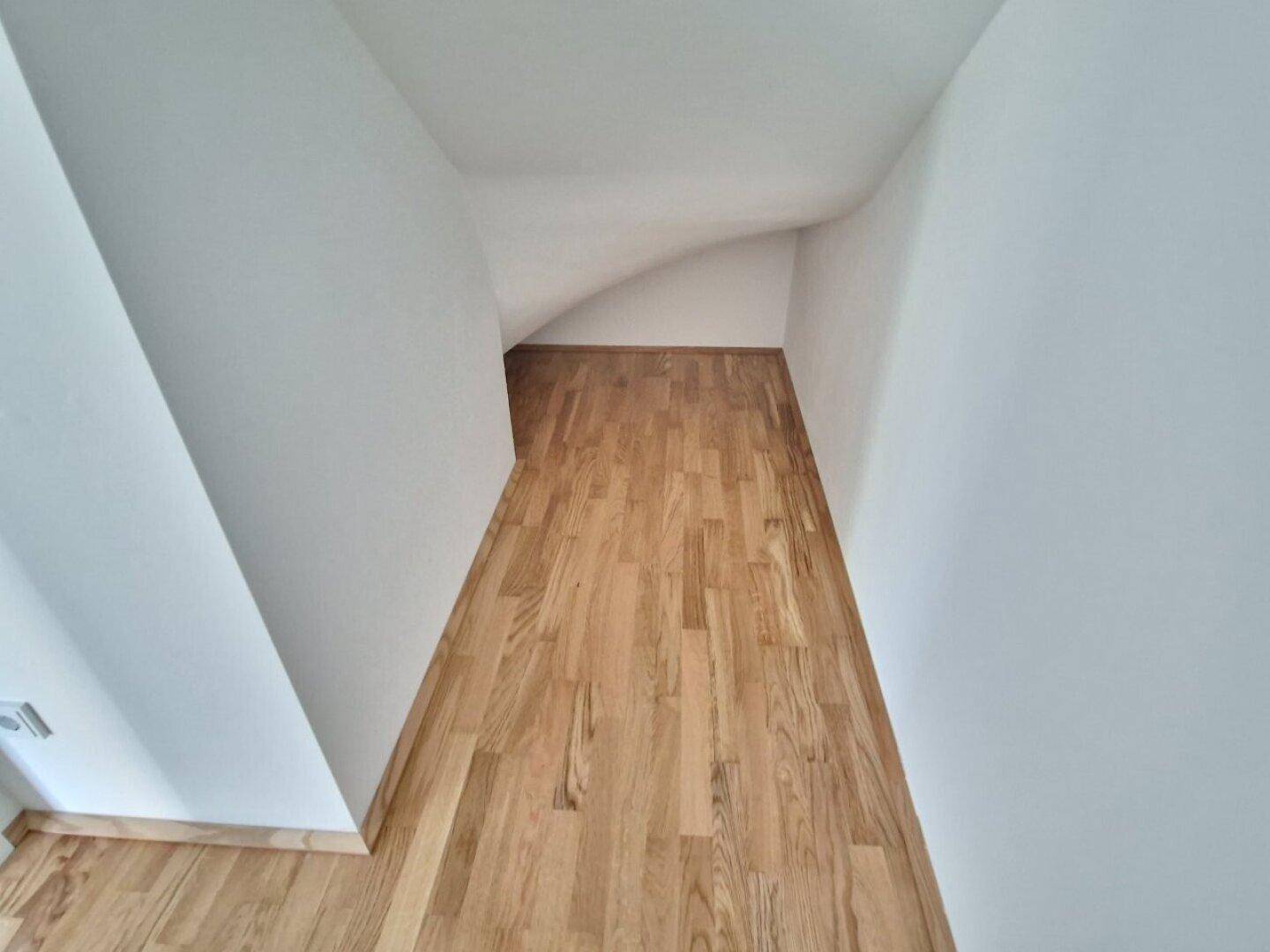 Dachbodenbereich mit Holzboden und schrägen Wänden, bietet zusätzlichen Stauraum.