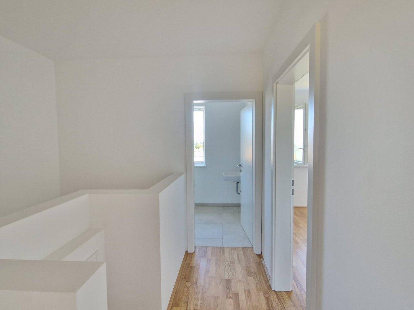 Flur im Obergeschoss mit Holzboden und Zugang zu Badezimmer und weiteren Zimmern.