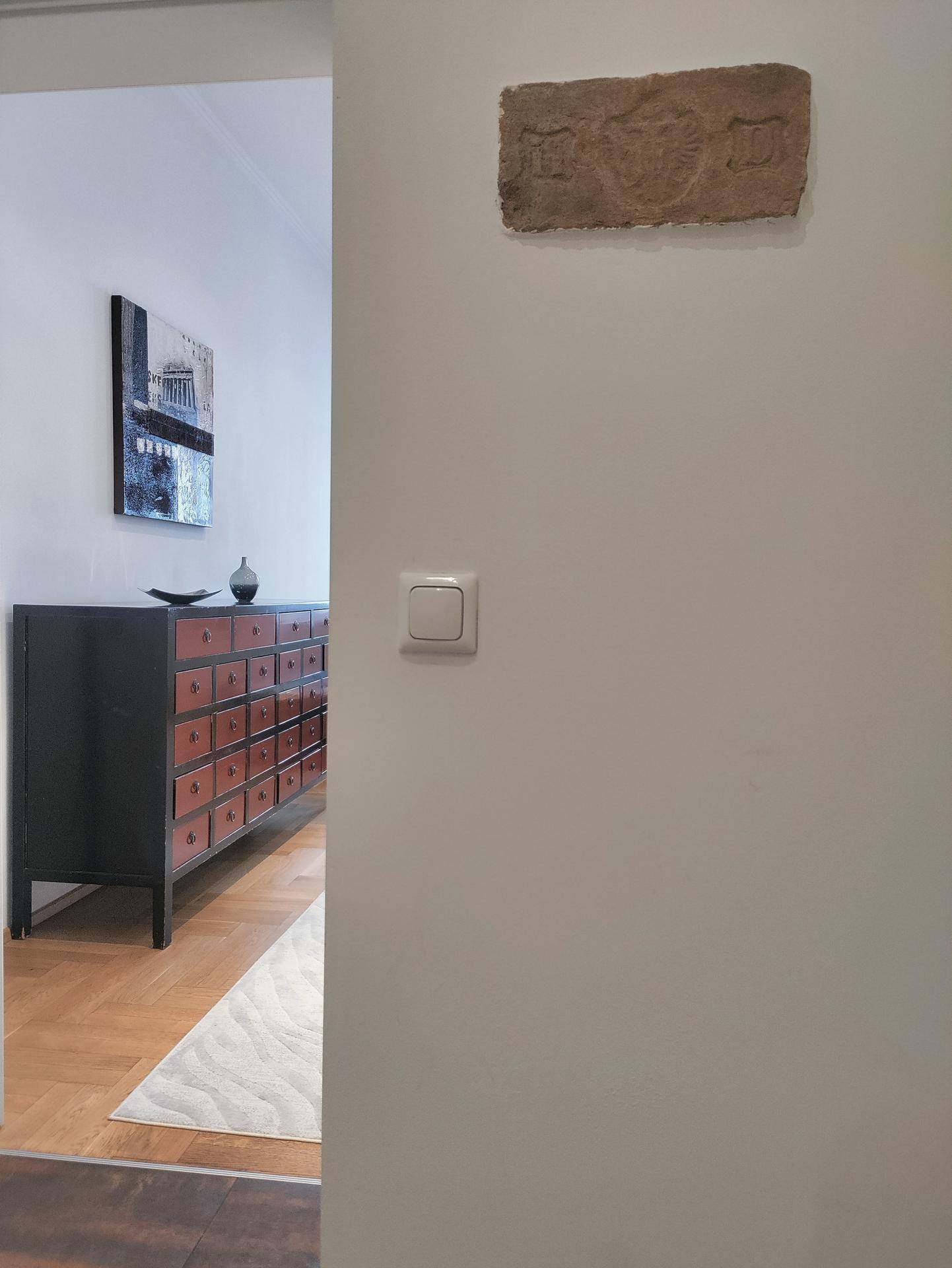 Übergangsbereich mit Holzboden und dekorativer Kommode im Hintergrund.