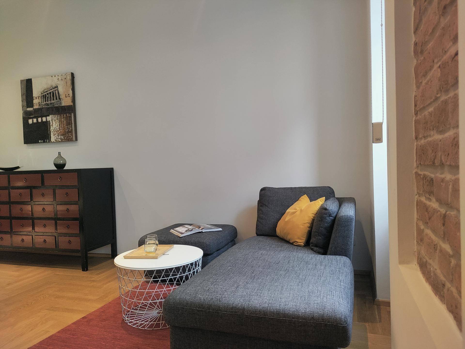 Gemütlicher Wohnbereich mit Chaiselongue, Couchtisch und dekorativer Kommode.