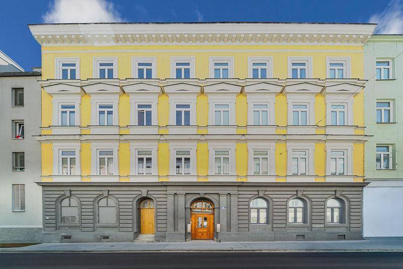 Historisches Gebäude mit gelber Fassade, vielen Fenstern und klassischer Architektur.