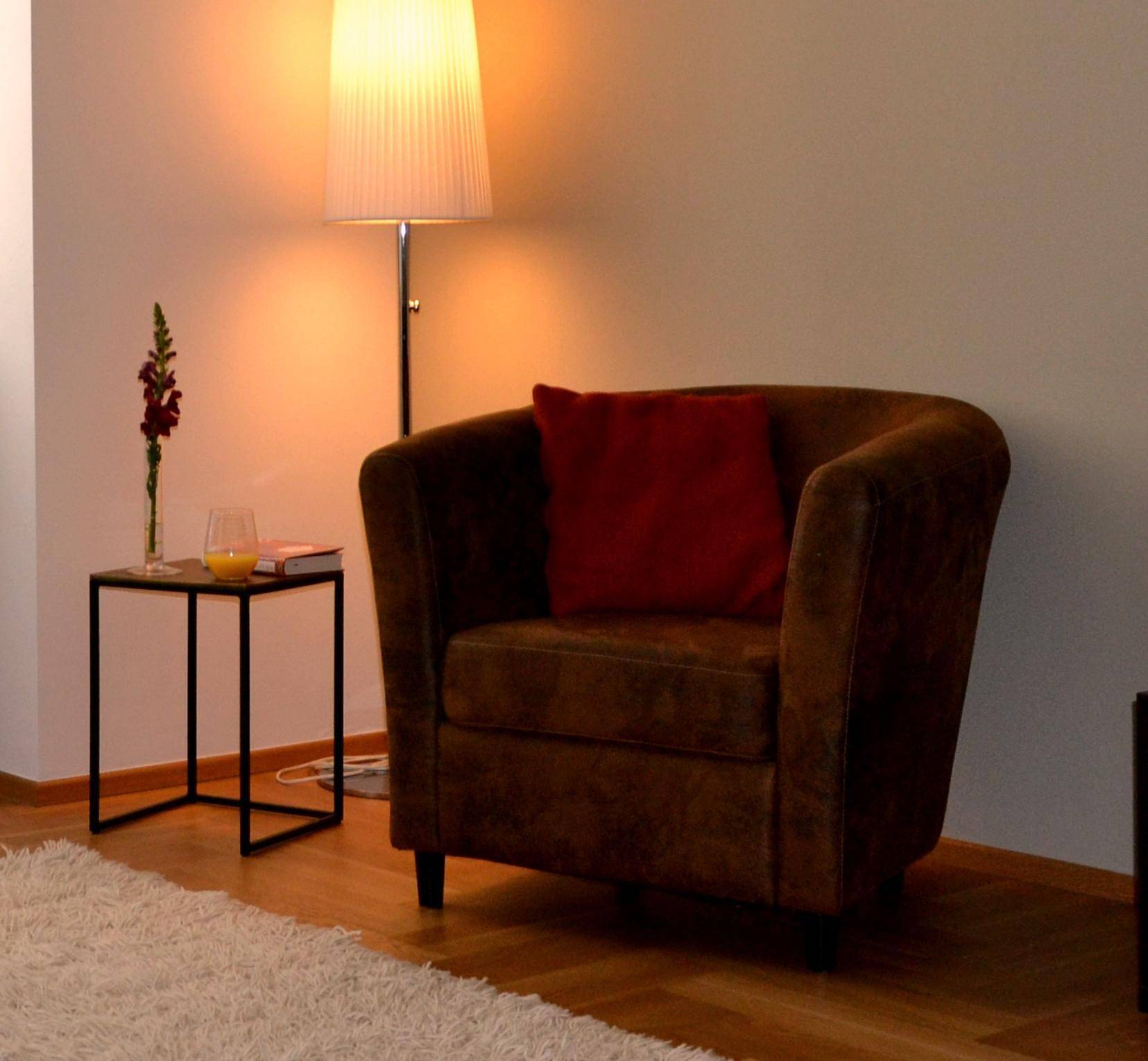 Gemütlicher Sessel mit Stehlampe und Beistelltisch in einem hellen Raum.