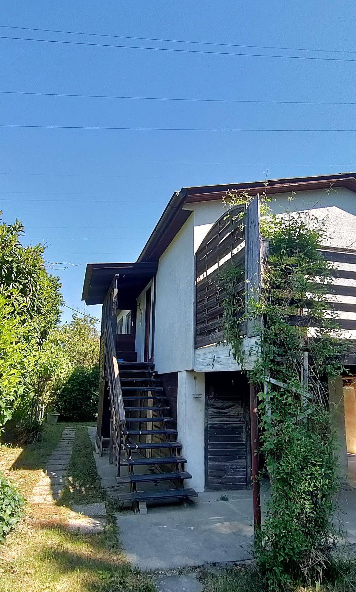 Seitenansicht des Hauses mit Außentreppe und Holzelementen an der Fassade.