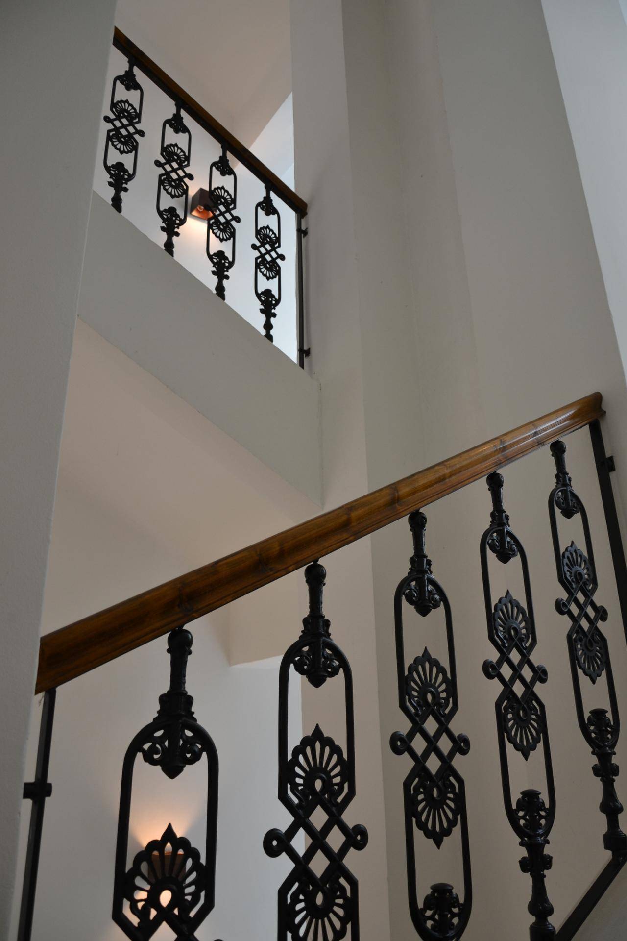 Elegantes Treppenhaus mit schmiedeeisernem Geländer und Holzhandlauf.