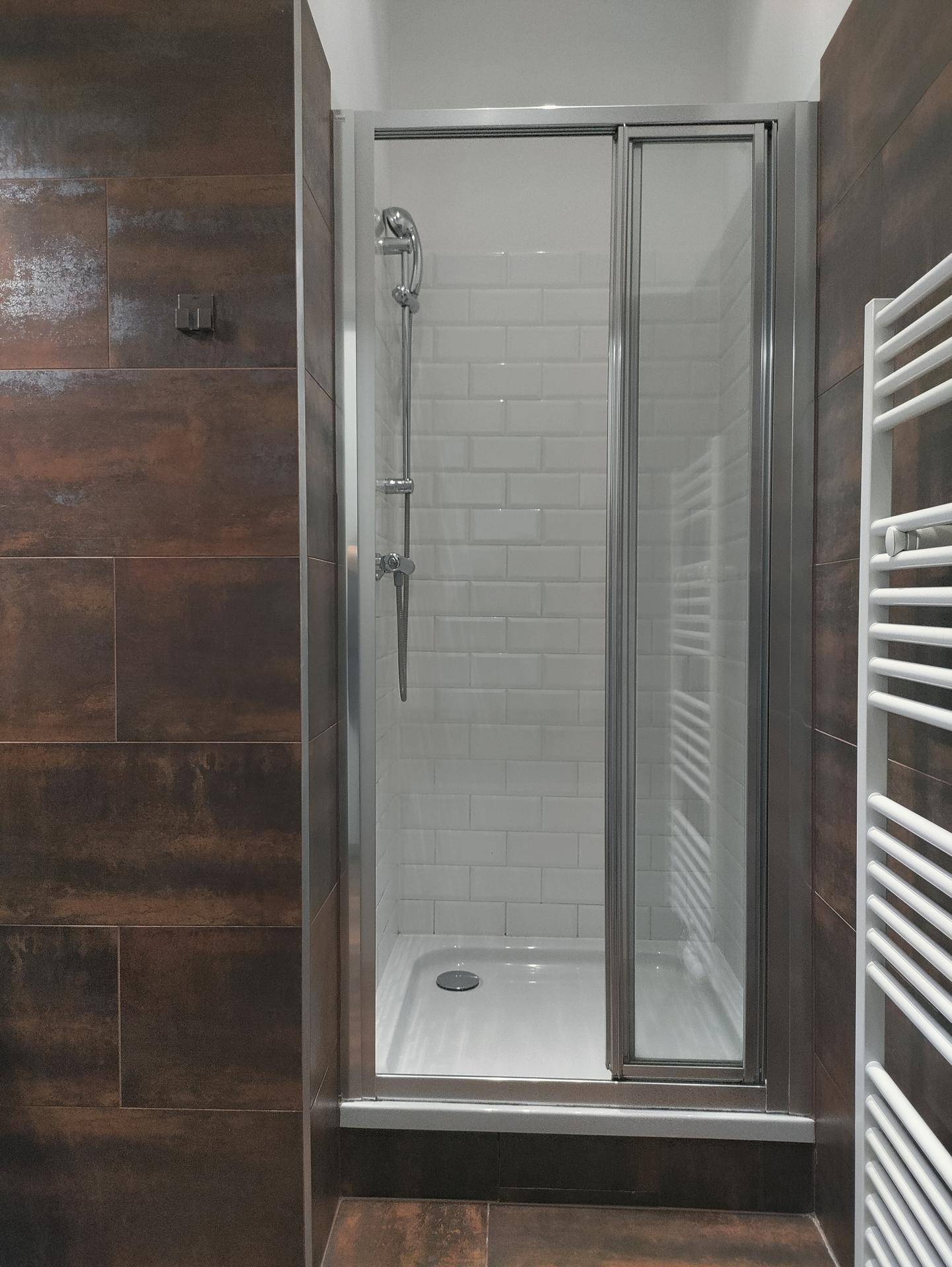 Modernes Badezimmer mit Duschkabine, weißen Fliesen und beheiztem Handtuchhalter.