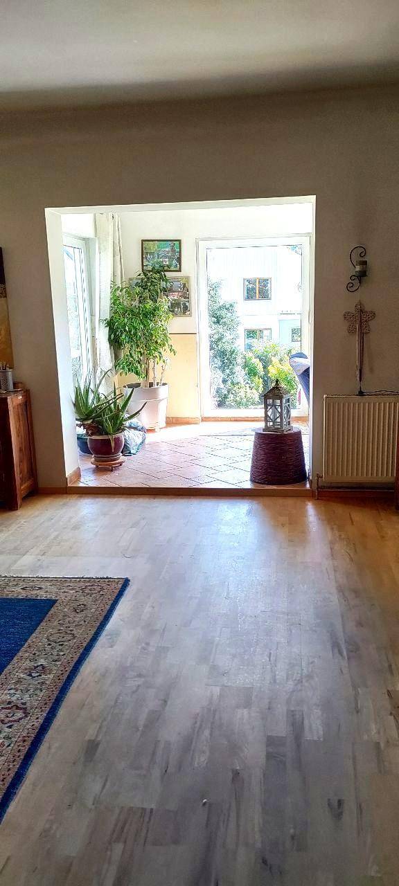 Heller Durchgang zu einem Außenbereich mit großen Glastüren und Topfpflanzen, mit Holzboden.