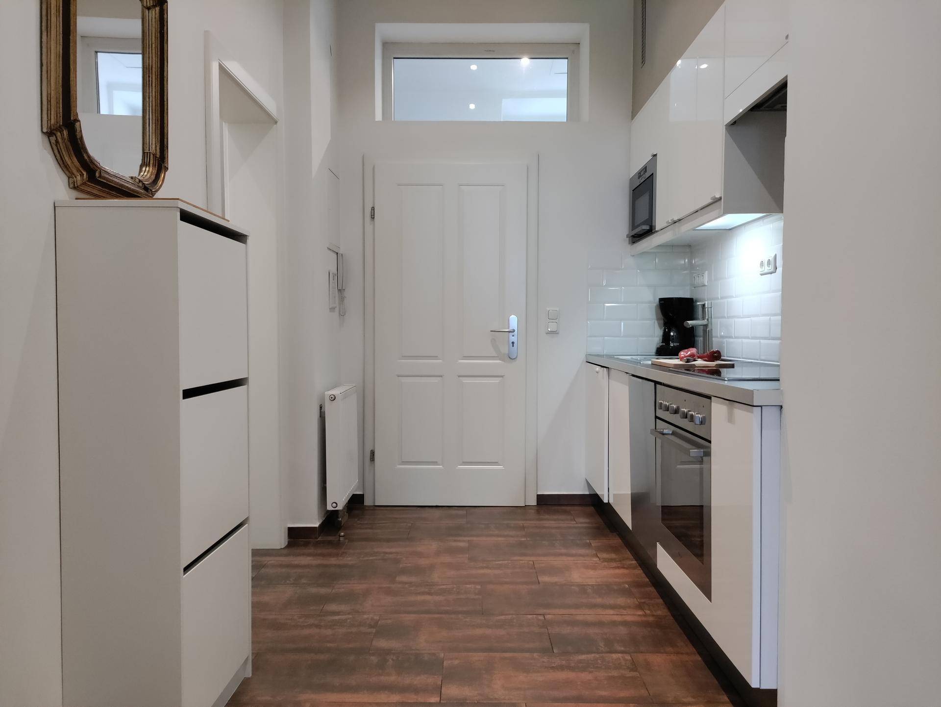 Eingangsbereich der Küche mit Schuhschrank und Blick auf die moderne Küchenzeile.