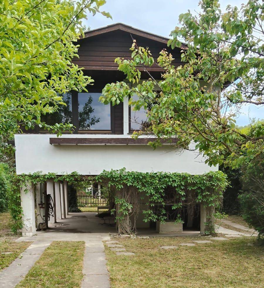 Ansicht des Hauses mit überdachtem Carport und üppiger Begrünung an der Fassade.