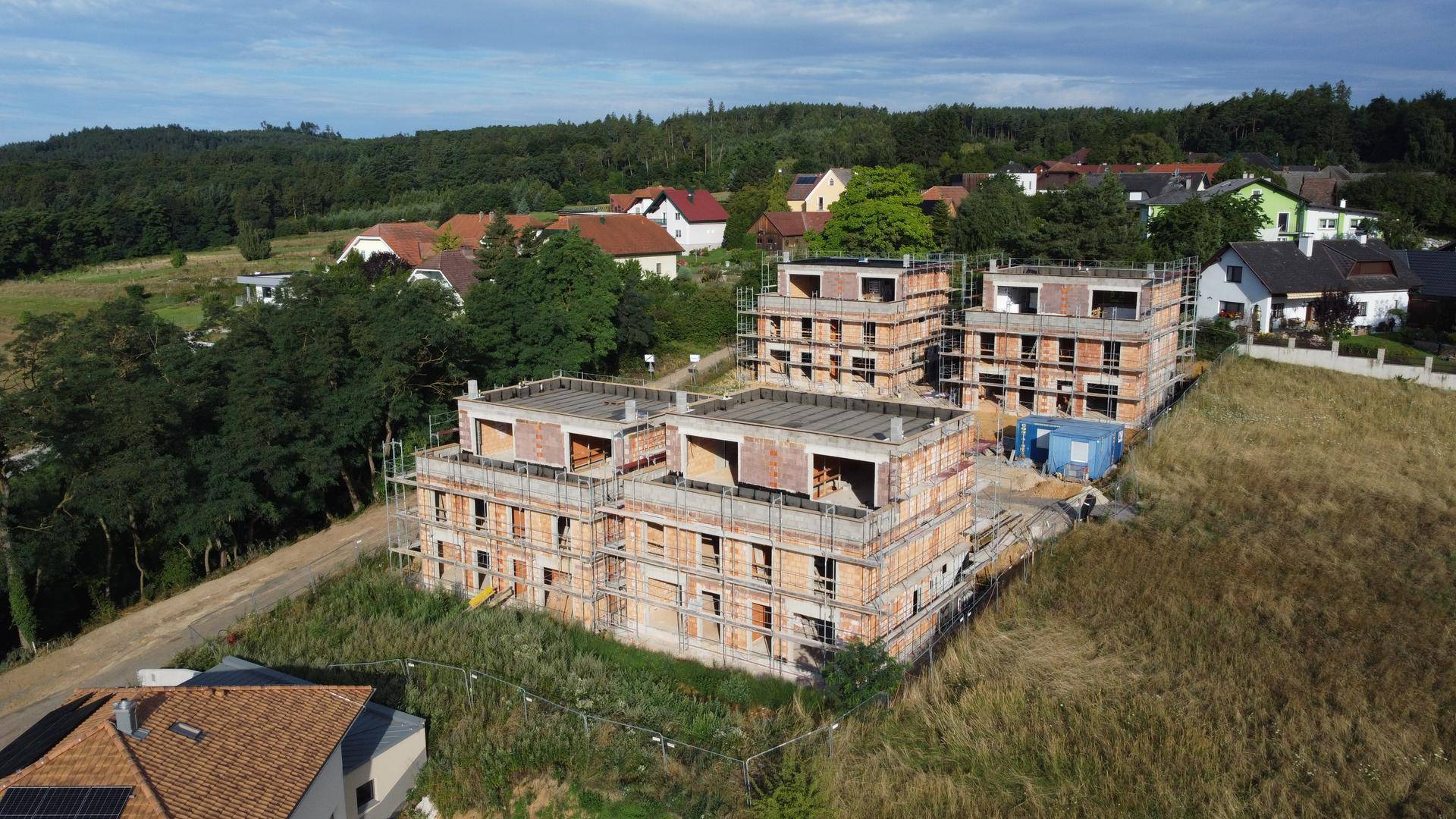 Luftbild der im Bau befindlichen Reihenhäuser mit Gerüsten und Blick auf die ländliche Umgebung.