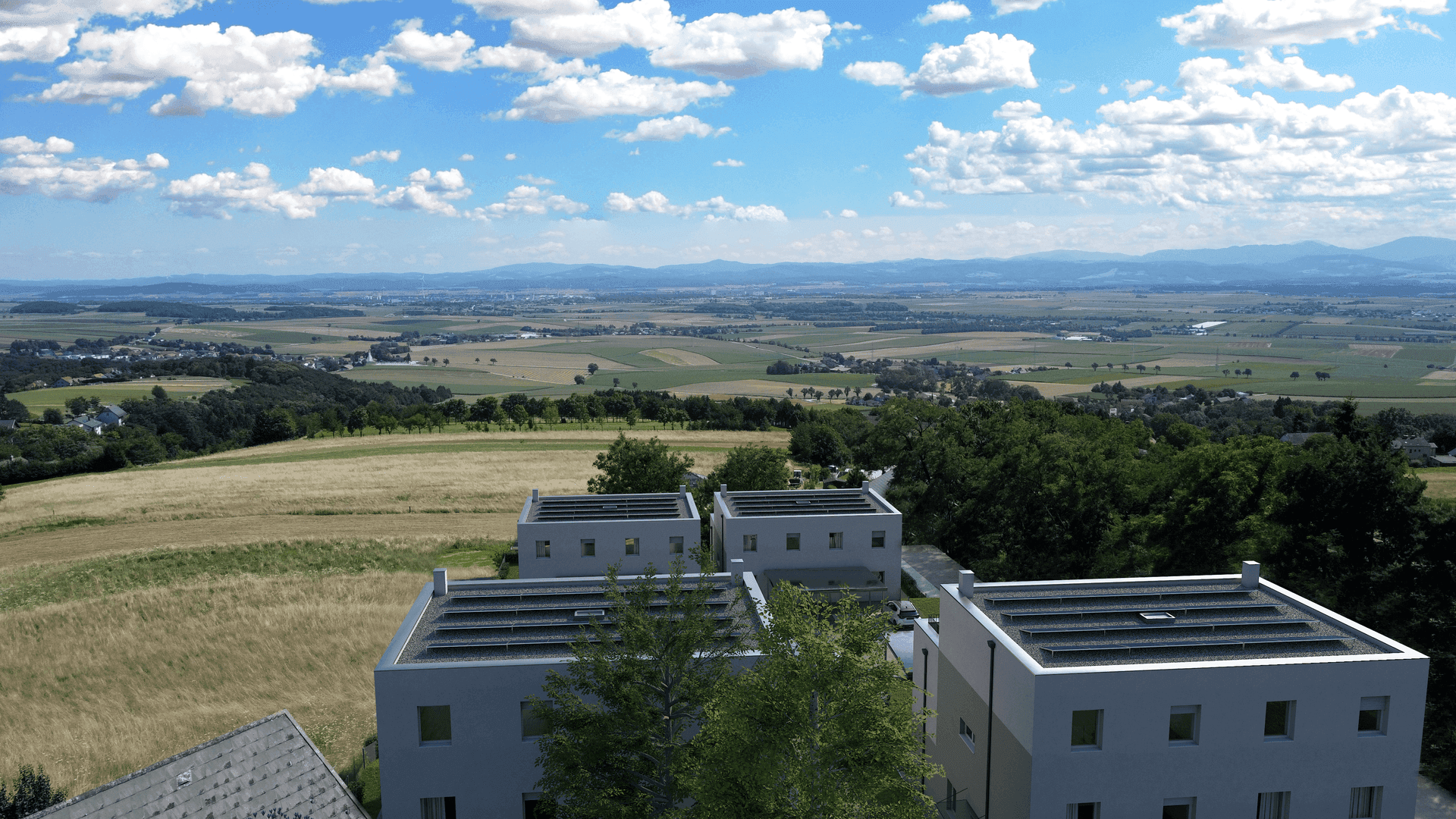 Luftaufnahme von Neubauten mit Photovoltaikanlagen auf den Dächern und weitem Blick über die Landschaft.