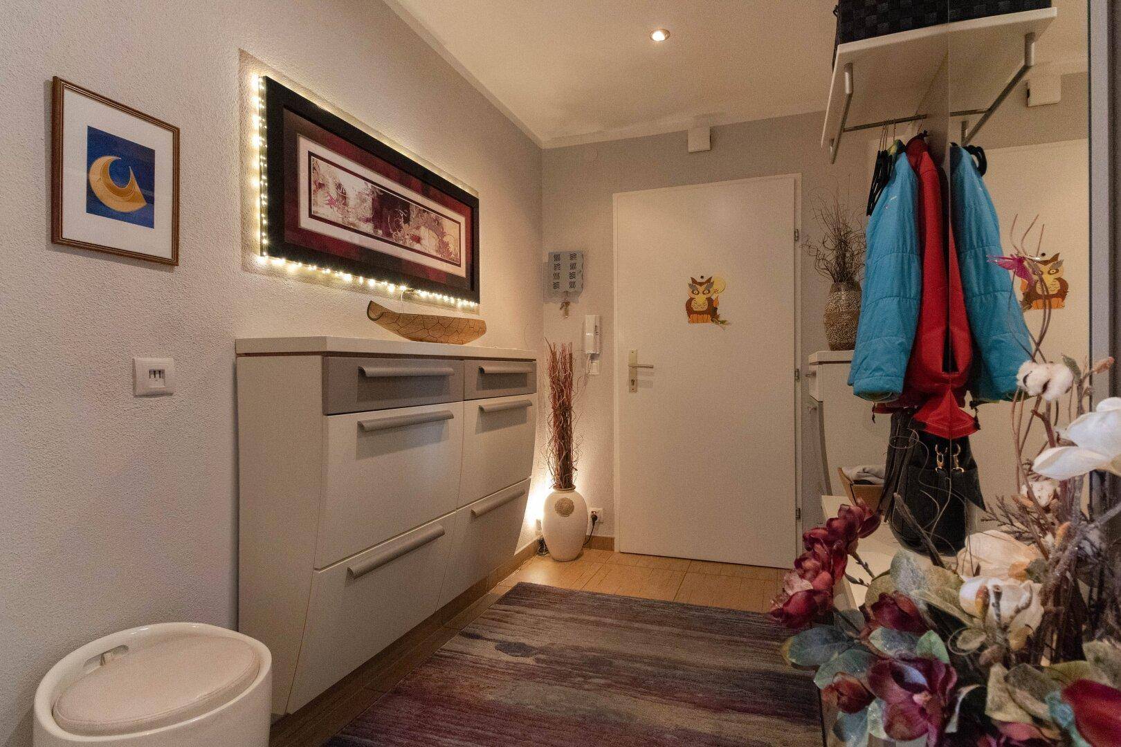 Eingangsbereich mit Schuhschrank, Garderobe und heller Beleuchtung.