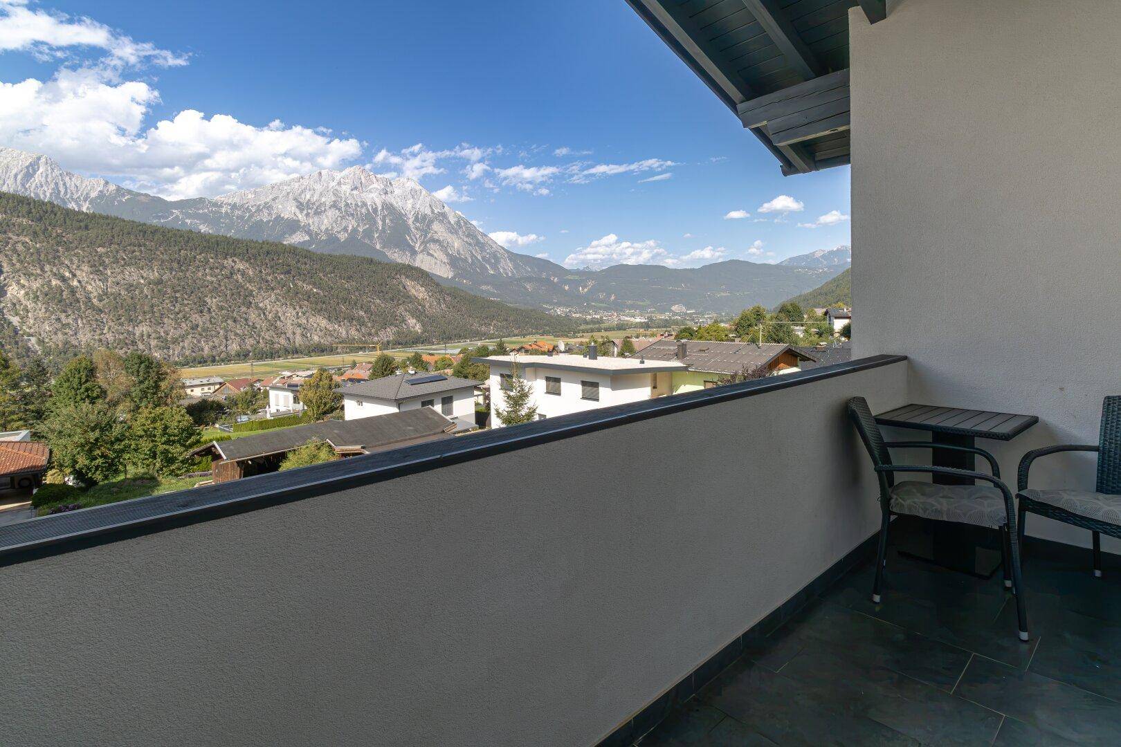 Kleiner Balkon mit Sitzgelegenheiten und einem weiten Blick auf die Berge und das Tal.