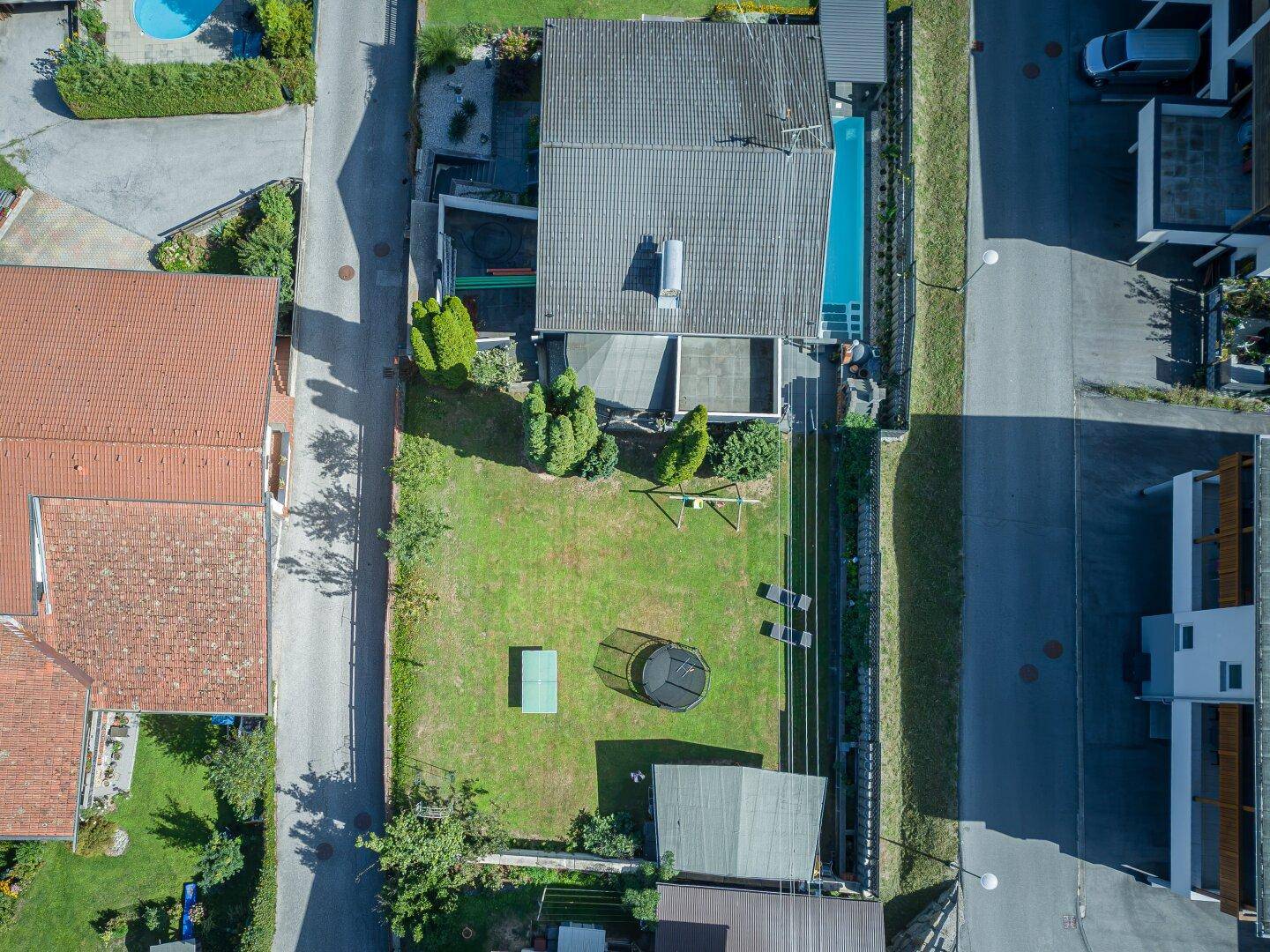 Luftaufnahme des Anwesens mit großem Garten, Pool, Trampolin und Schaukel im Grünen.