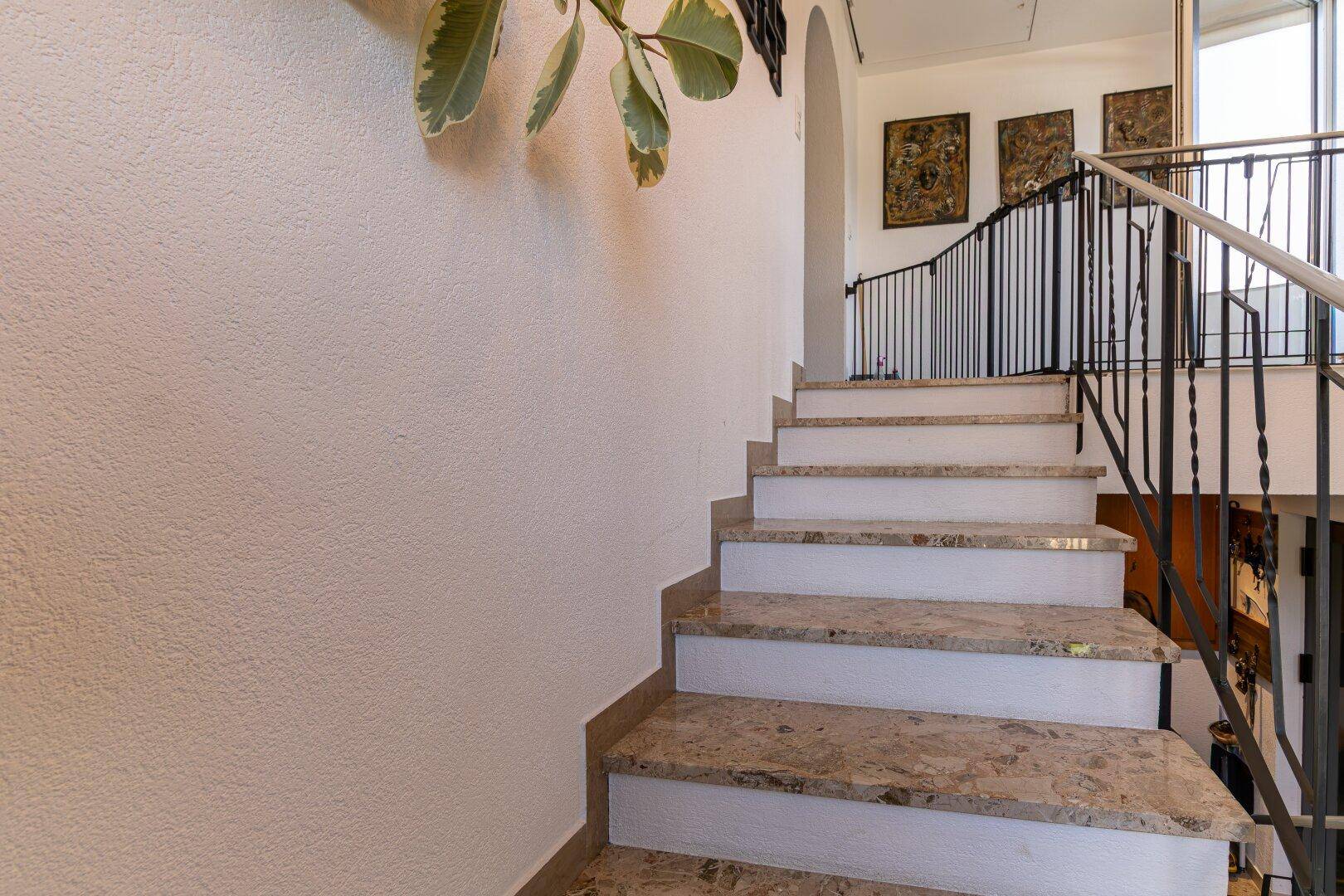 Elegante Treppe mit Marmorstufen und schmiedeeisernem Geländer, die zu den oberen Etagen führt.