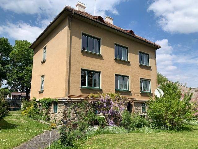 Rückansicht der Villa mit Steinfundament und blühendem Blauregen an der Fassade.