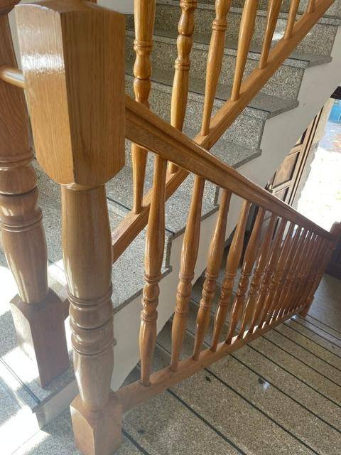 Detailaufnahme eines Holztreppengeländers mit Granitstufen, das Eleganz verleiht.