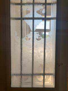 Dekoratives Fenster mit Milchglas und schmiedeeisernen Gittern, das für Privatsphäre sorgt.