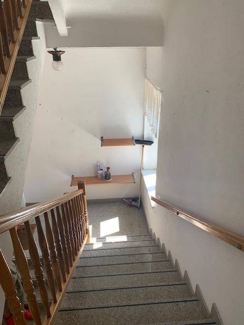 Blick von oben auf eine Treppe mit Holzgeländer und Granitstufen, die die verschiedenen Etagen verbindet.