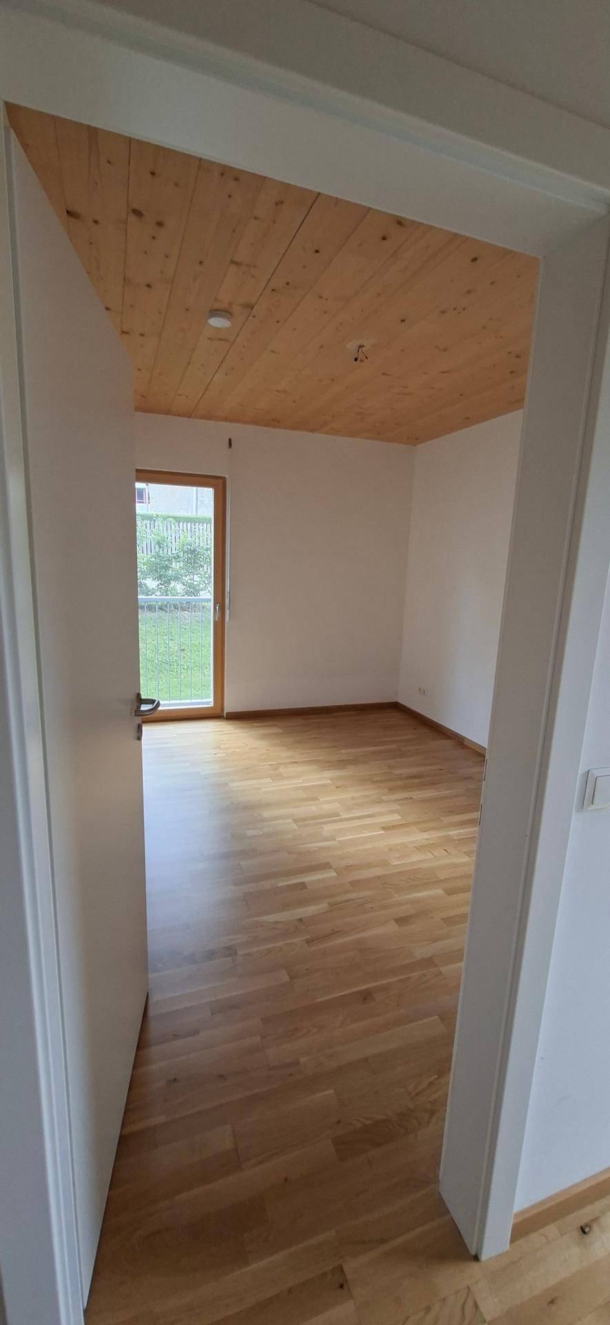 Leeres Zimmer mit Holzboden und Holzdecke, bereit für individuelle Gestaltung.