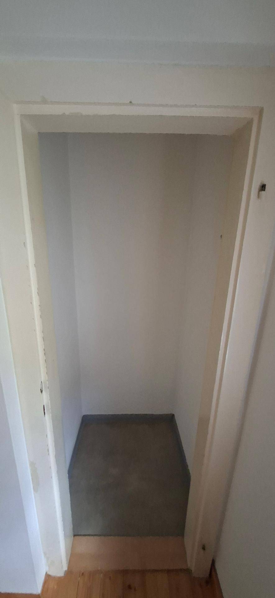 Kleiner, heller Nischenbereich mit grauem Boden, ideal als Abstellraum oder begehbarer Schrank.