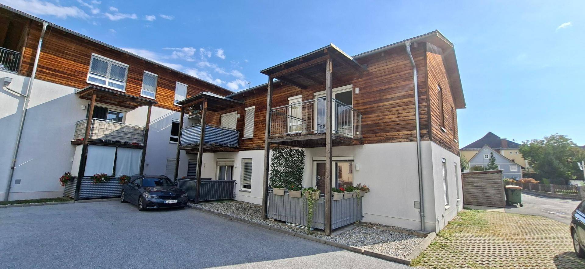 Gebäudekomplex mit mehreren Balkonen und Parkplätzen, umgeben von einer gepflegten Außenanlage.