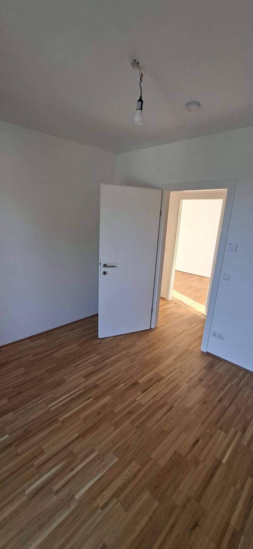 Geräumiges Schlafzimmer mit Holzparkettboden und viel Tageslicht, bereit zur individuellen Gestaltung.