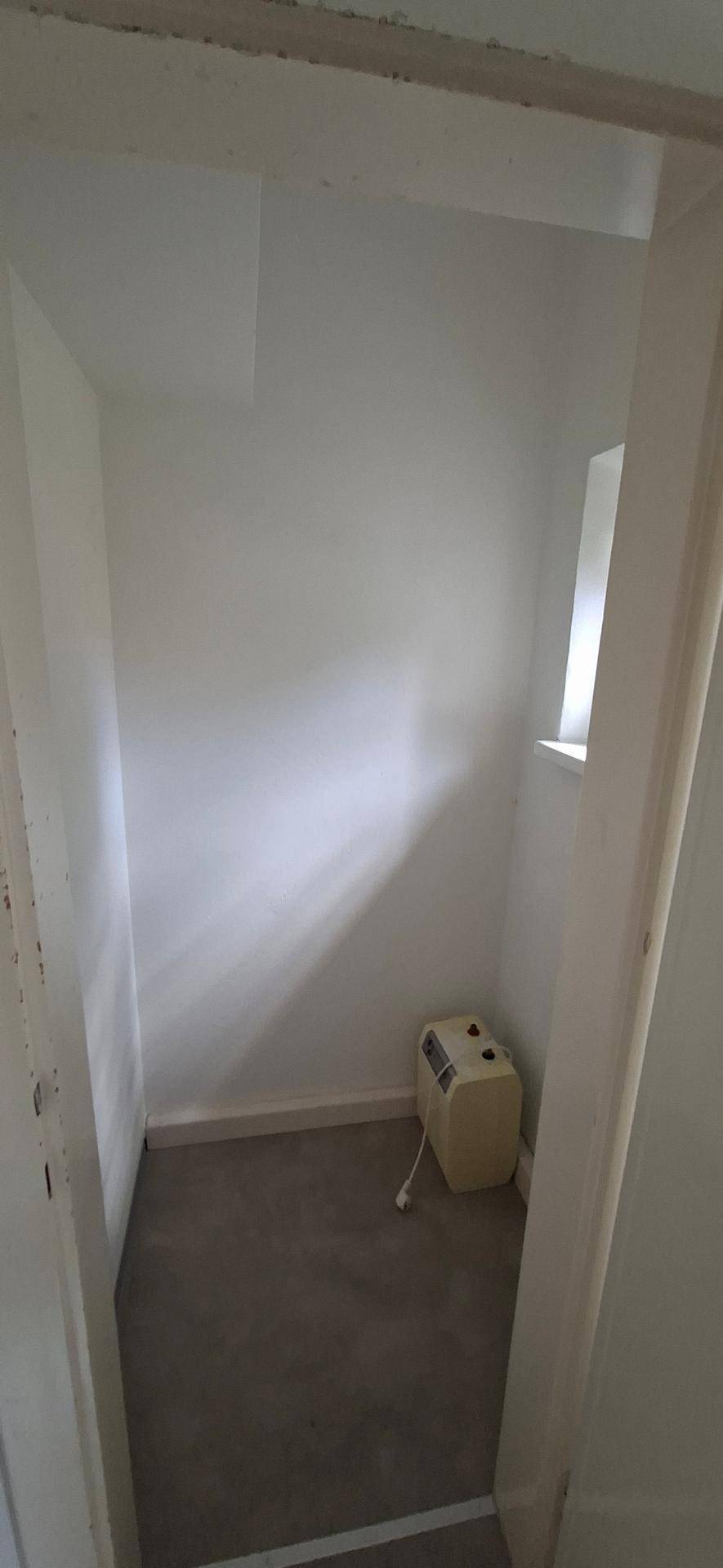 Kleiner Abstellraum mit Teppichboden und einem kleinen Fenster, ideal für zusätzlichen Stauraum.