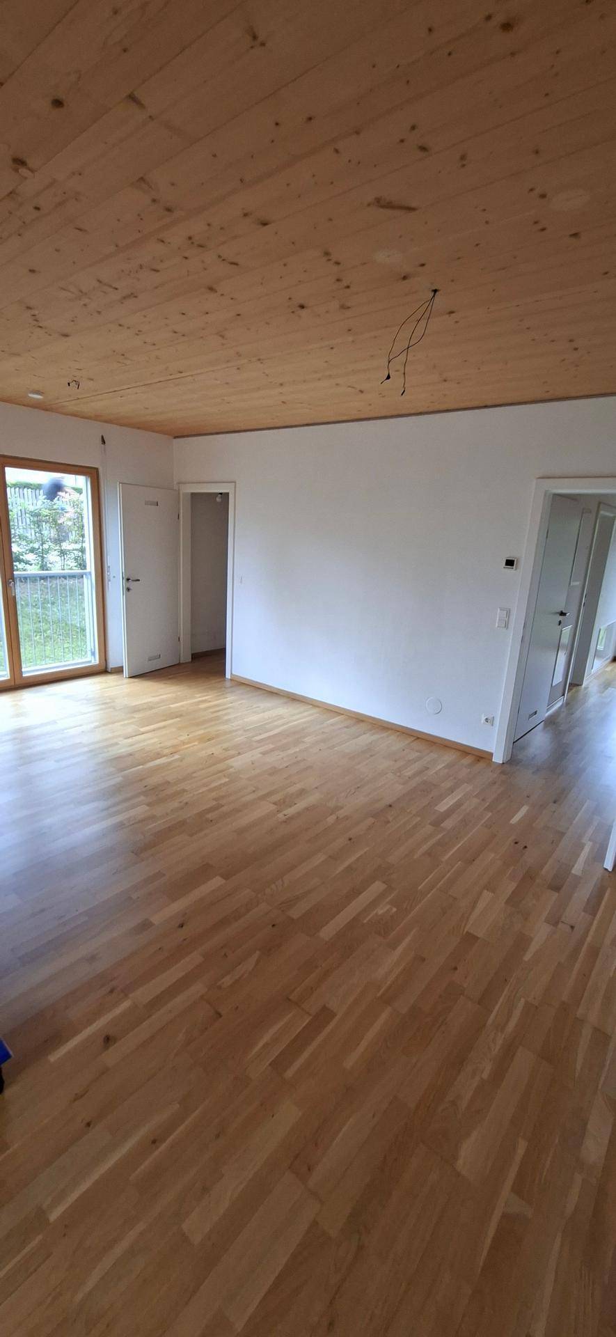 Großzügiger Wohnbereich mit Holzboden und Holzdecke, bietet vielseitige Gestaltungsmöglichkeiten.