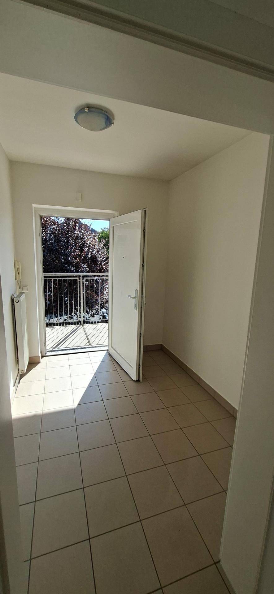 Heller Flur mit Fliesenboden und direktem Zugang zu einem sonnigen Balkon, der viel Licht spendet.