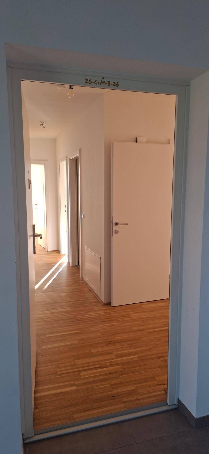 Heller Flur mit Holzparkettboden und Zugang zu verschiedenen Zimmern der Wohnung.