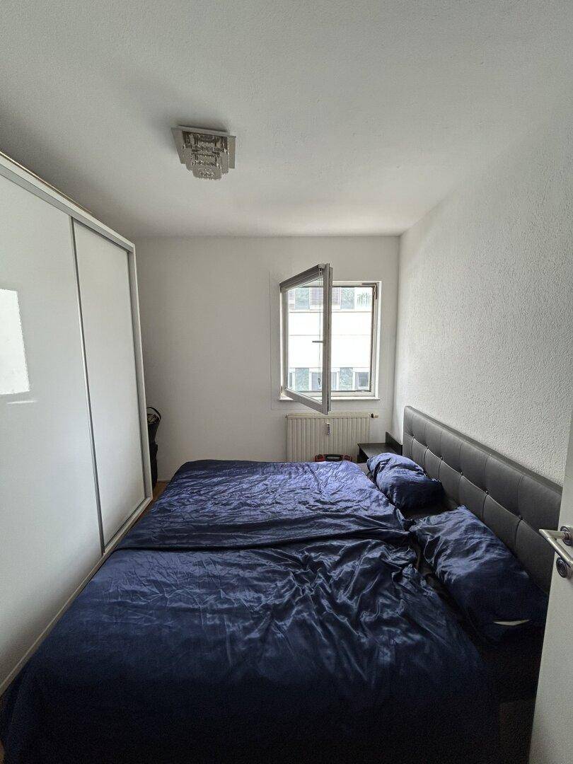 Schlafzimmer mit Doppelbett, großem Kleiderschrank und Fenster für natürliches Licht.