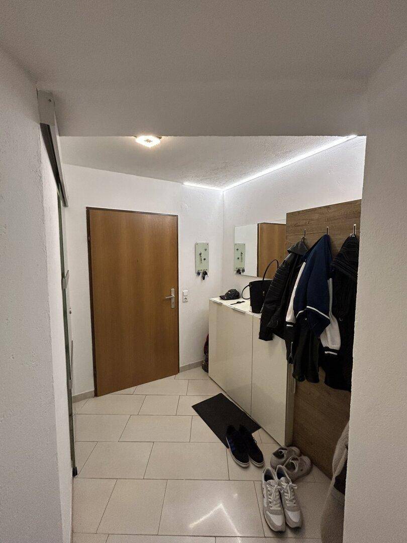 Eingangsbereich mit Garderobe, Spiegel und indirekter Beleuchtung für eine einladende Atmosphäre.
