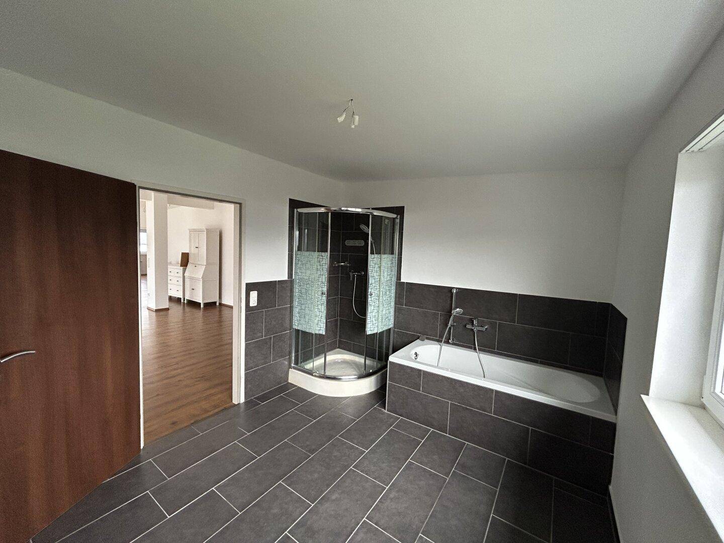 Geräumiges Badezimmer mit Duschkabine, Badewanne und modernen Fliesen.