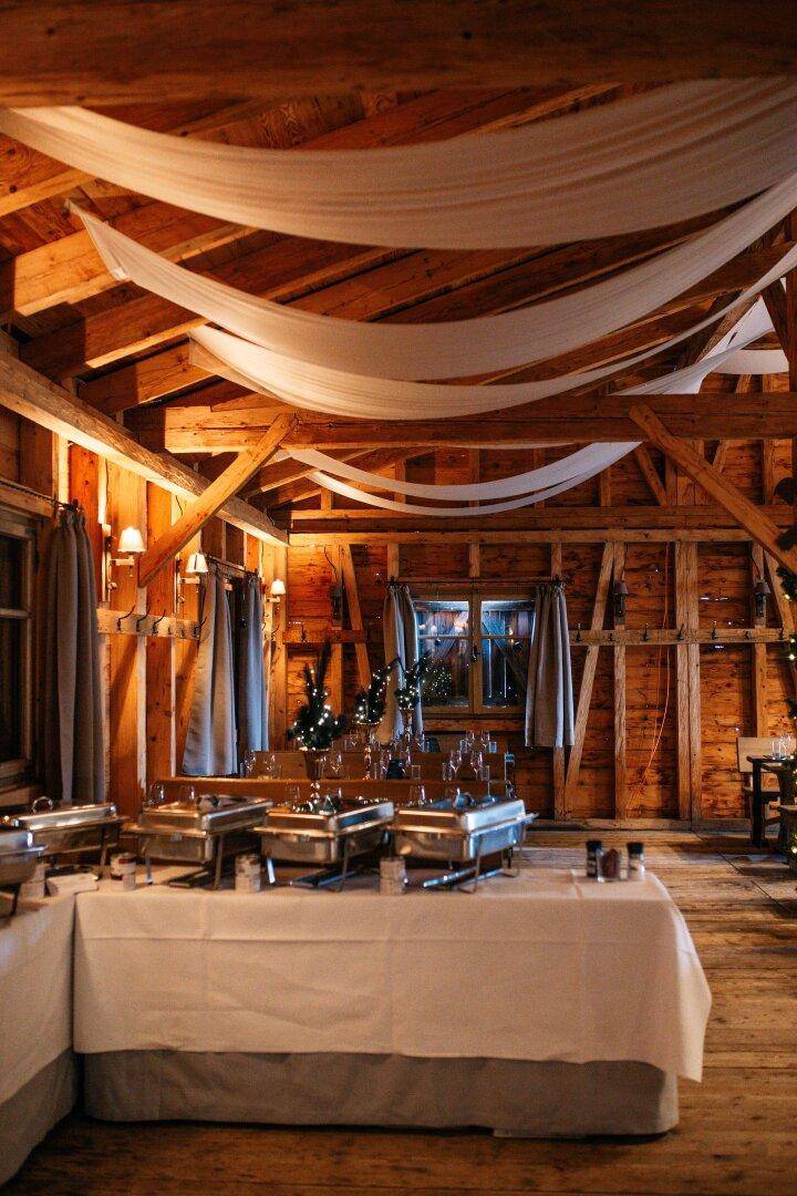 Buffetbereich mit weißen Tischdecken und drapierter Decke, umgeben von Holzwänden.