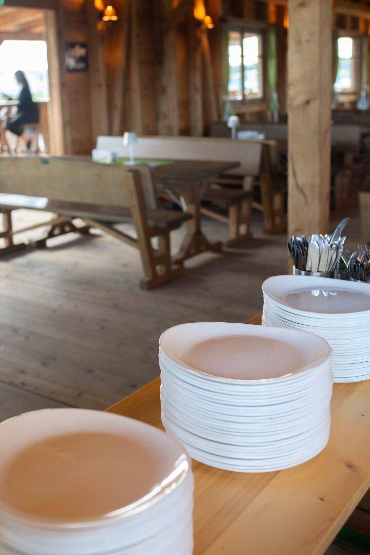 Stapel von Tellern auf einem Holztisch, bereit für die Bewirtung der Gäste im Festsaal.