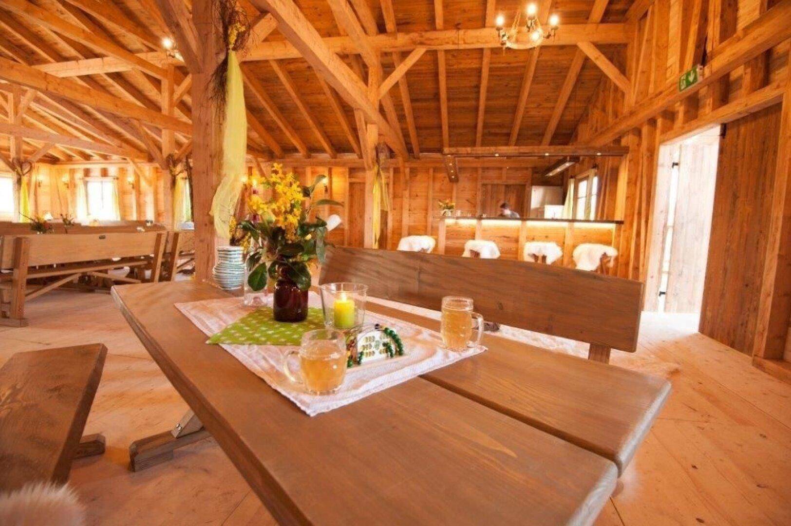 Detailansicht eines dekorierten Holztisches mit Bänken und Blick auf den Barbereich.