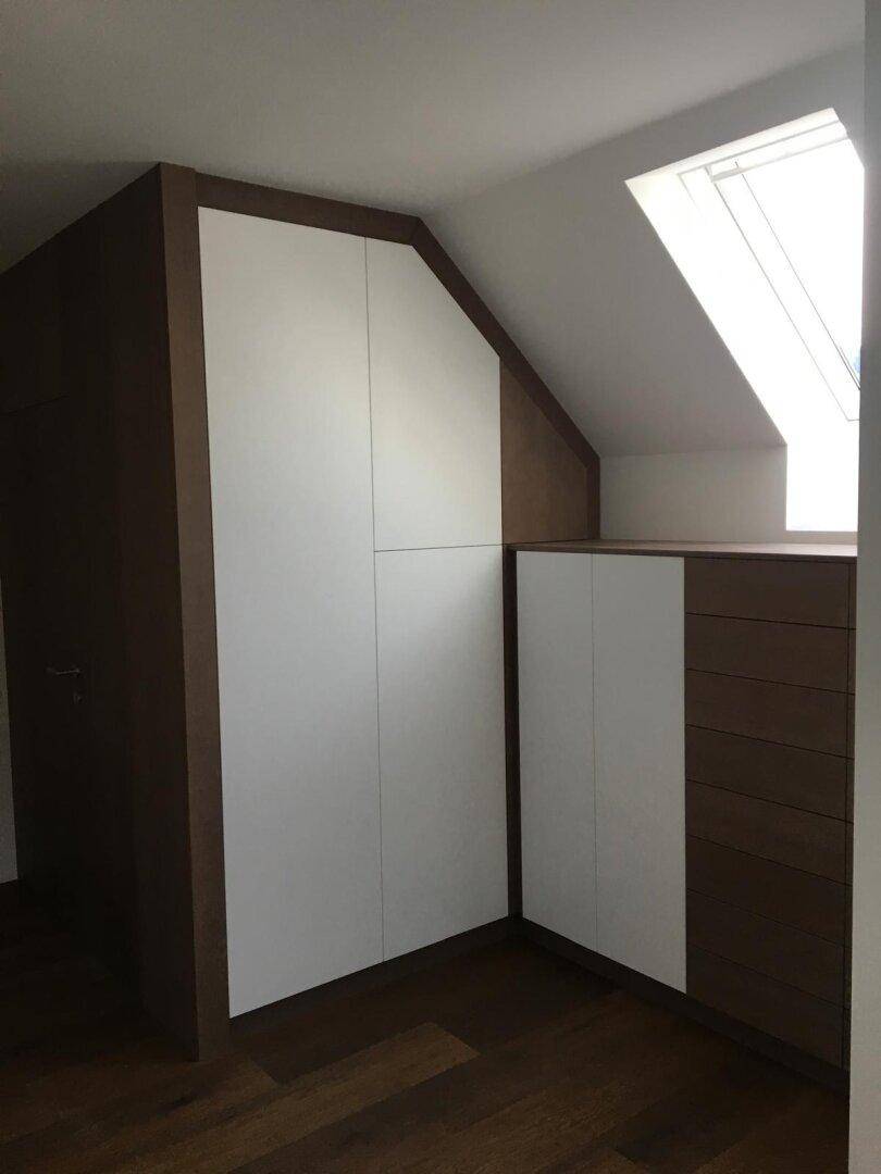Maßgefertigte Einbauschränke unter der Dachschräge mit integriertem Dachfenster.