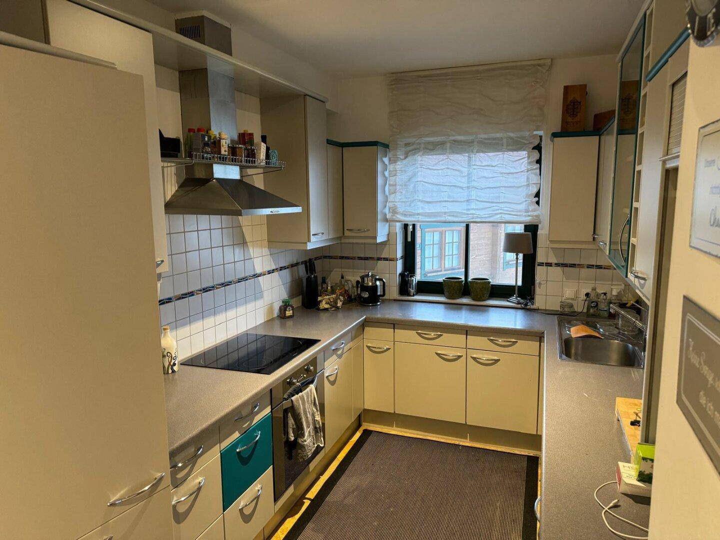 Helle Küche mit cremefarbenen Schränken, Fliesenrückwand und modernen Kochgeräten.