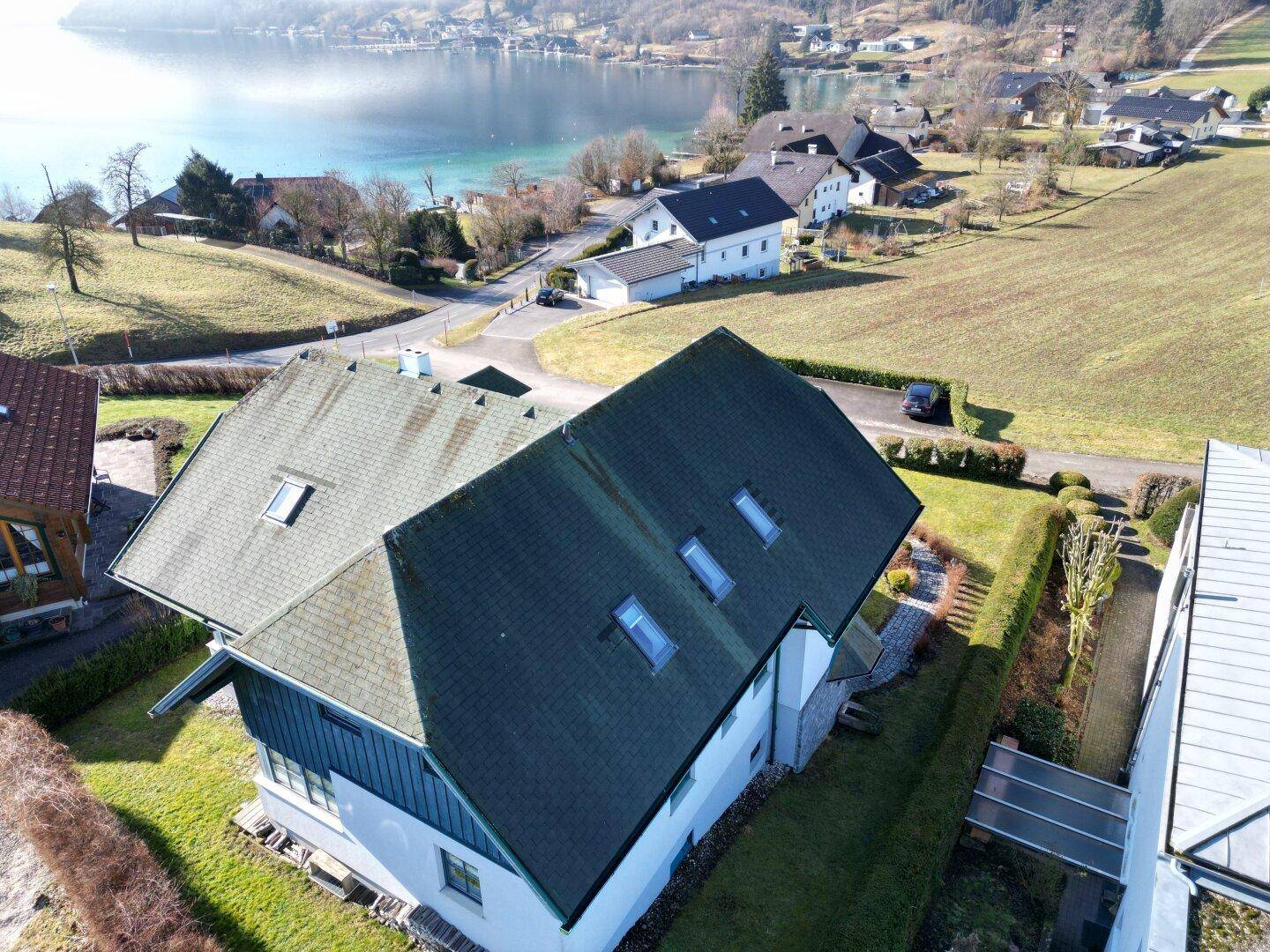 Dachansicht des Hauses mit mehreren Dachfenstern und weitem Blick auf den See.