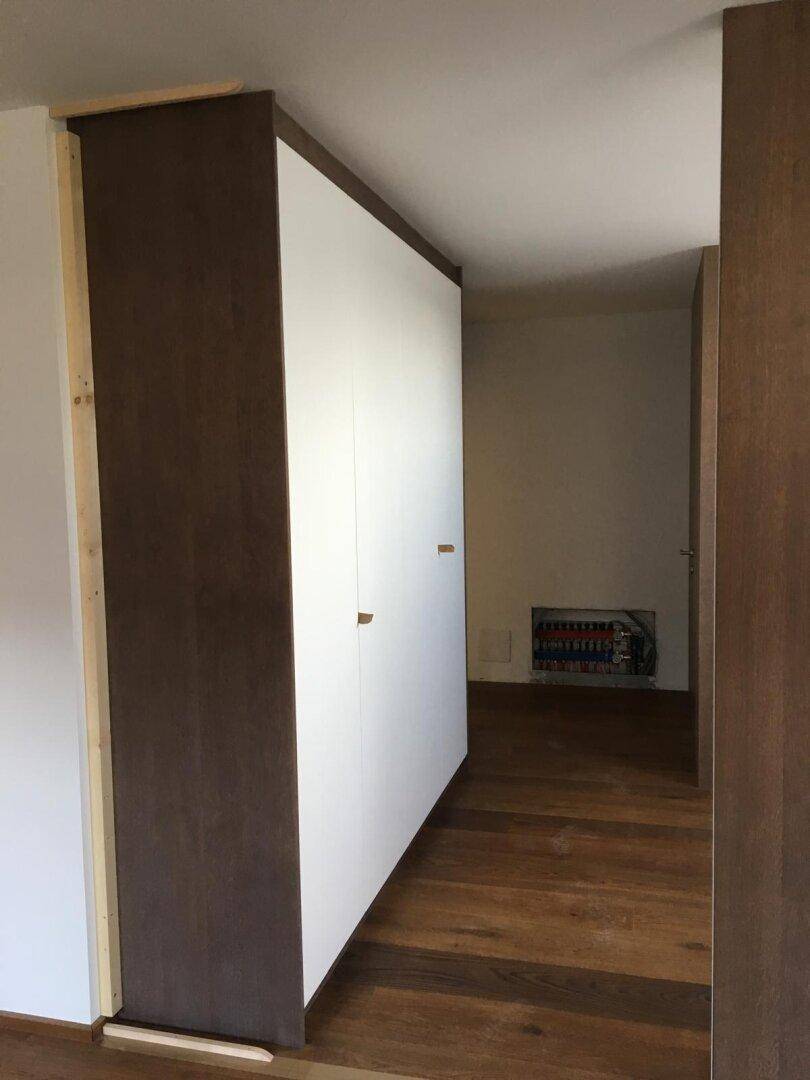 Flur mit integriertem Einbauschrank und elegantem Holzfußboden.