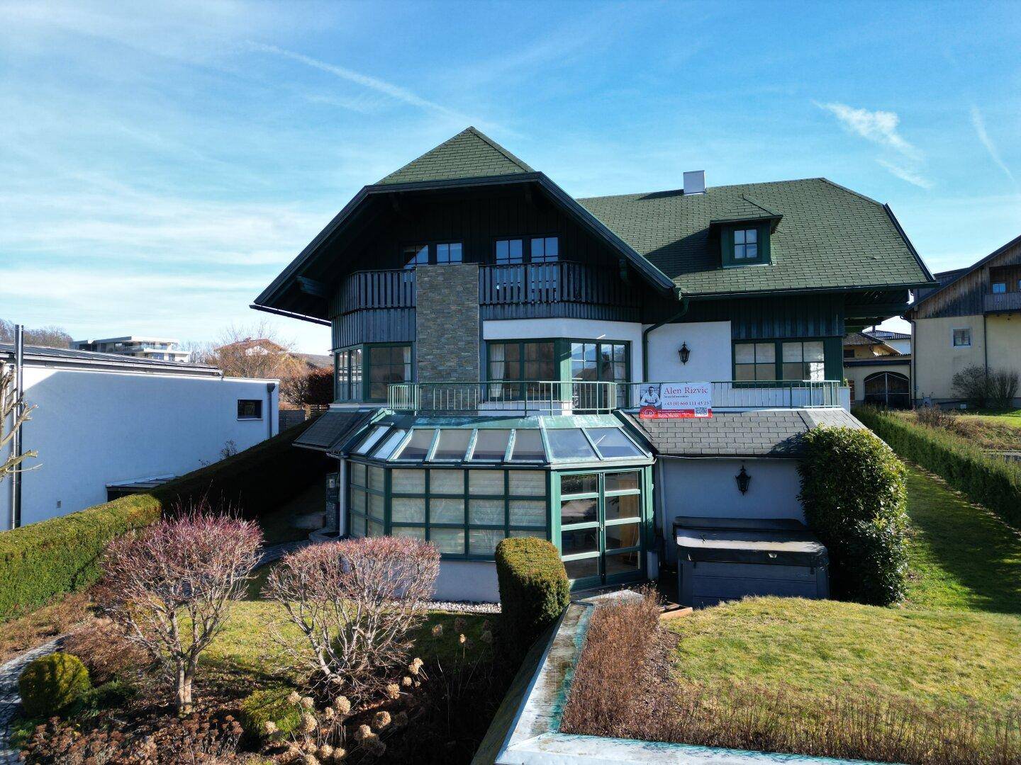 Frontansicht des Hauses mit Wintergarten, gepflegtem Vorgarten und traditioneller Architektur.